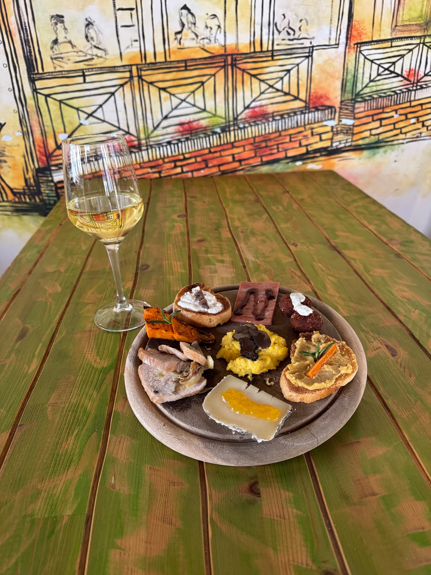 Tagliere di degustazione con crostini e un calice di vino bianco